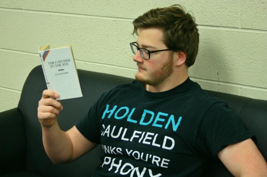 Senior Chris Miller reads "The Catcher in the Rye". He is wearing a shirt that references the book. 