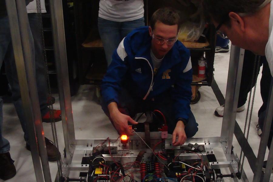 Senior Dalton Nofs works on Team 5150s robot in the pit at the Kettering University district event. Nofs traced the wiring of the CAN cable between motor controllers.