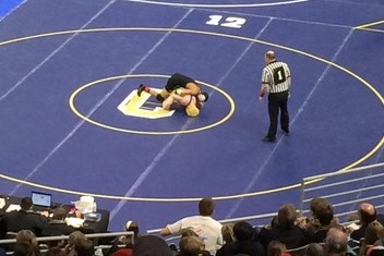 Senior Jakob Chapman (yellow headgear) competes in a match at the Division 2 individual state final at 119 pounds. Chapman earned his fourth All-State honor placing fifth.