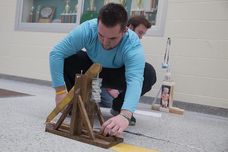 Senior Kyle Alburtus loads  a cork ball into the sling of his trebuchet.  The ball was launched 9.7 meters.