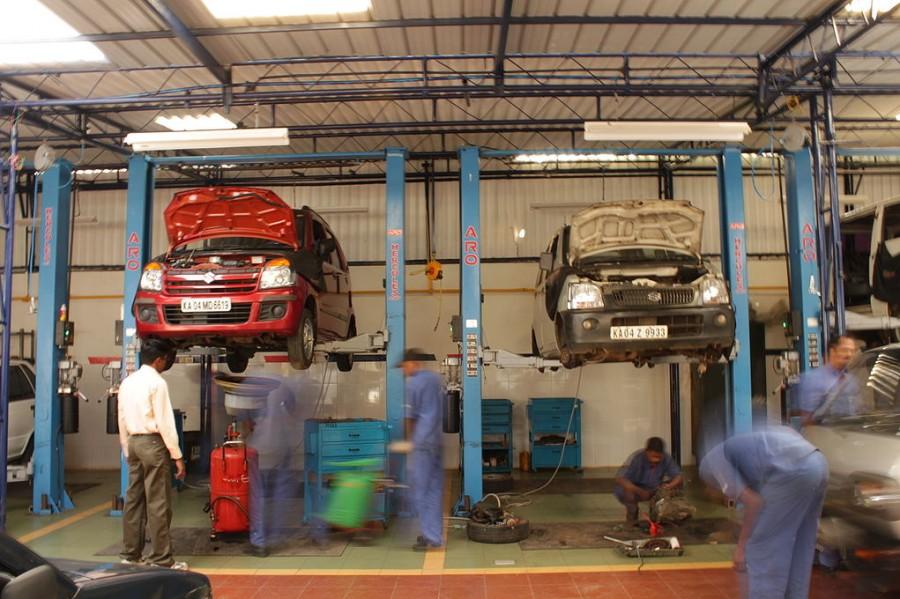 Mechanics work on cars in an automotive shop. 