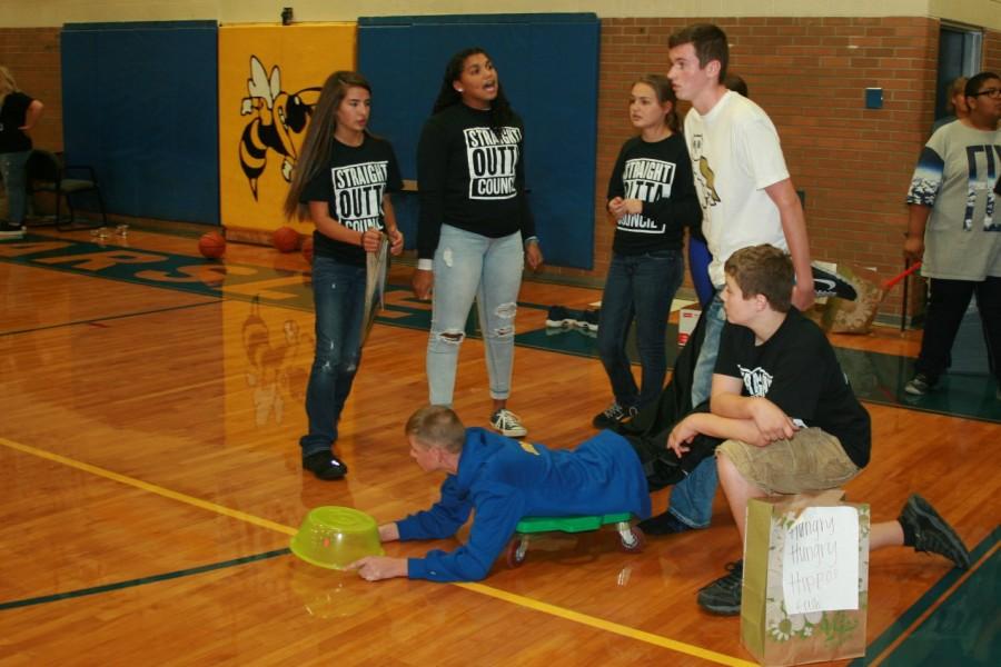 Marshall Judd (skooter) is pushed by Taron Diehl as part of the freshman team in Hungry, Hungry Hippos as Student Council members cheer for them.
