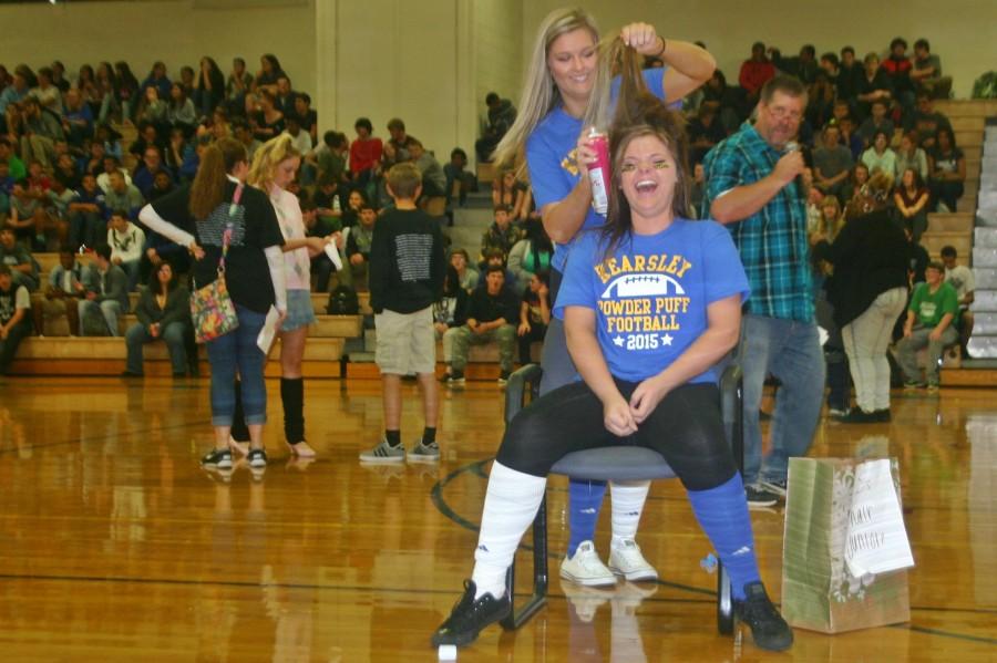 Venessa Rivera (sitting) gets her hair styled by Rachel Tolley in the 80s Hair Jungle contest during the pep assemble, Monday, Oct. 5. Both girls are juniors.