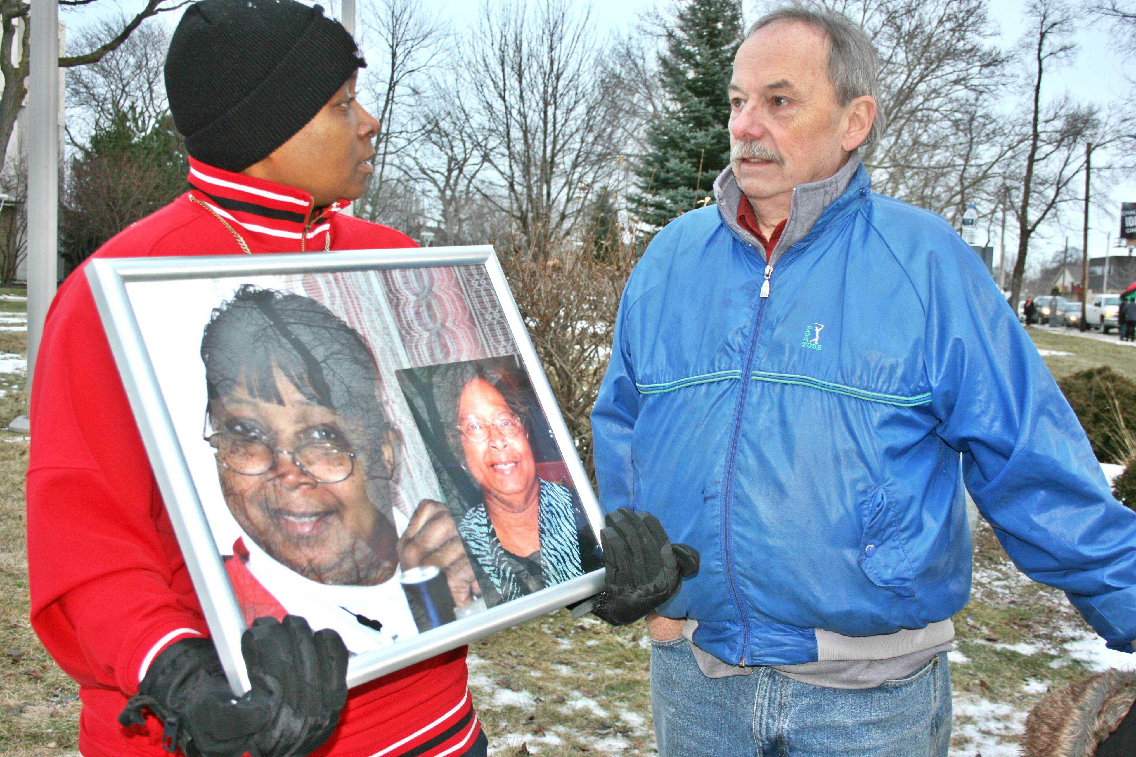 Holding a picture of her mother, Ms. Cholyanda Brown tells a man the story of her mother's death due to Legionnaire's disease at a Flint clean water protest outside Flint City Hall on Saturday, Jan. 16.