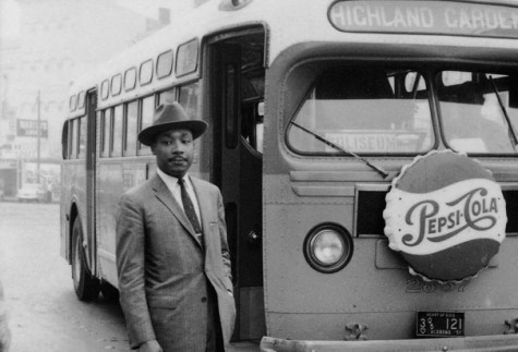 The Rev. Dr. Martin Luther King Jr. stands outside of a Montgomery bus.