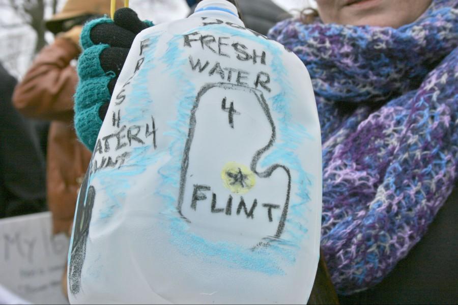 A protestor holds a water jug promoting clean water at a rally outside of Flint City Hall on Saturday, Jan. 16.