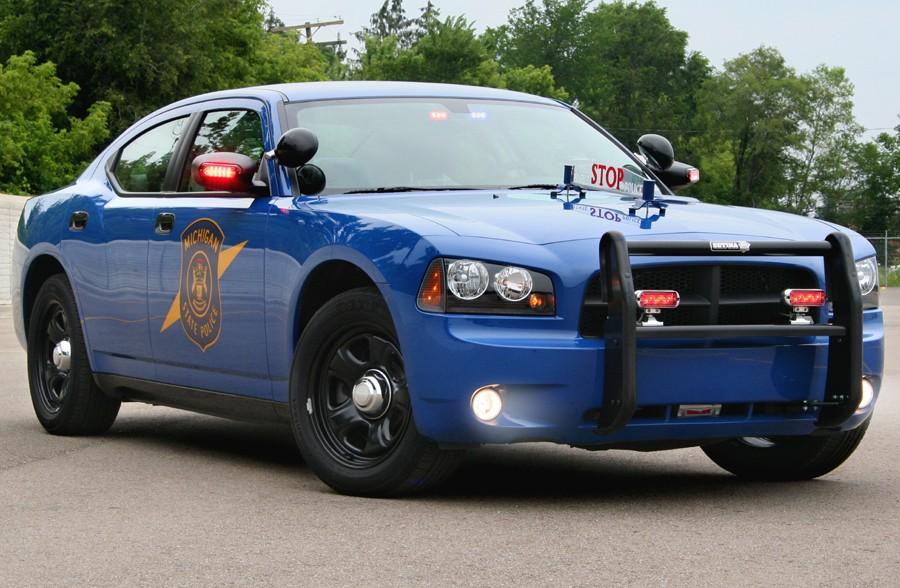 A 2006 Michigan State Police Dodge Charger flashes its red lights from its grill and the backside of its mirrors.