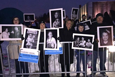 People hold up pictures of the children of flint who are drinking contaminated water.