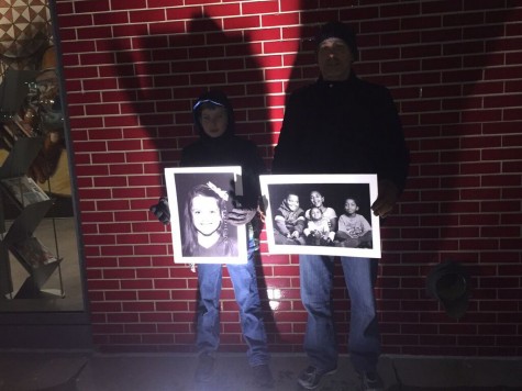 A father and son stand with pictures of Flint children.