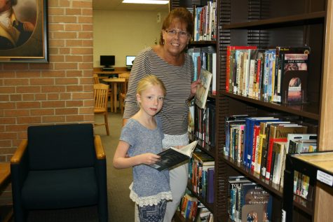Mrs. Sally Brandt and her granddaughter, Brooklyn Zaneske put away books in the media center.