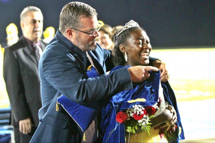 Mr. Brian Wiskur, principal, clasps the queens cloak on senior Kaylee Hill after she was named 2017 homecoming queen Friday, Oct. 13.