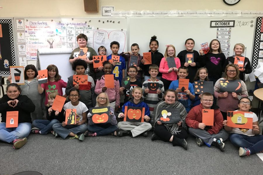 Mrs. Rae Puffers fourth-grade class at Fiedler Elementary shows off its Halloween cards on Friday, Oct. 27. The cards were made by high school students from Ms. Diane Hunts classes. Hunts classes also donated candy to the fourth-graders for Halloween.