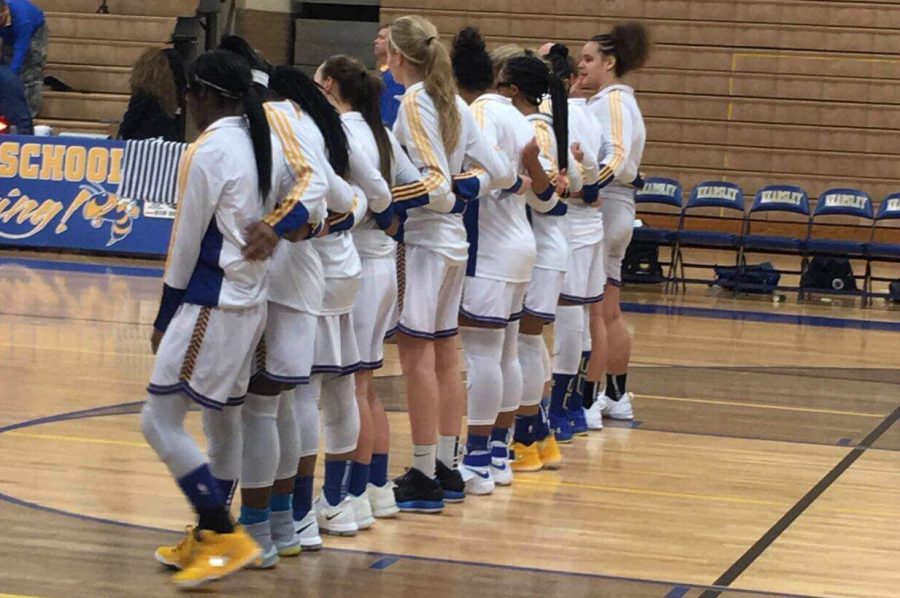 The girls basketball team gathers together for the national anthem in a game earlier this year. 