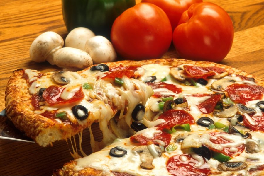 A supreme pizza with tomato sauce, cheese, pepperoni, peppers, olives, and mushrooms. melted cheese is typically stretched into hanging threads.