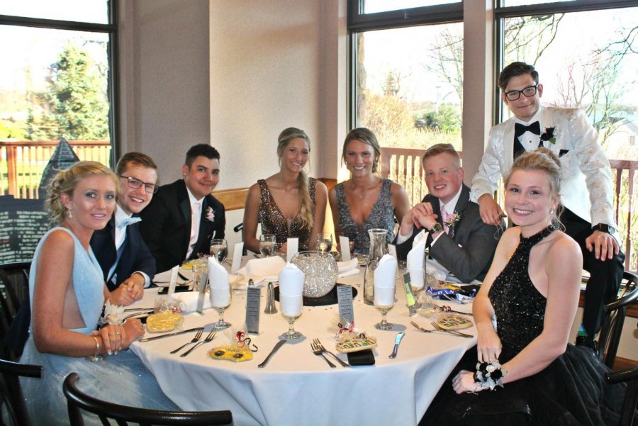 Seniors gather around the table while waiting for their meal at prom.