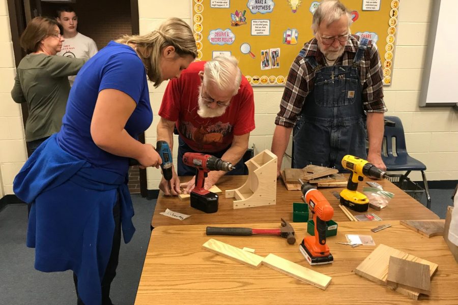 Liberty Anderson, eighth-grader, (left) learns to make a birdhouse with members of the Eastern Michigan Woodworkers at Kearsley High School, Wednesday, June 6.