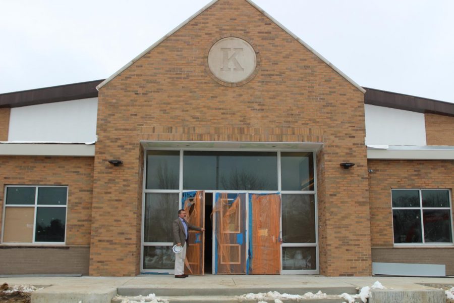 Mr. Brian Wiskur, principal, holds the door open for the new entrance.