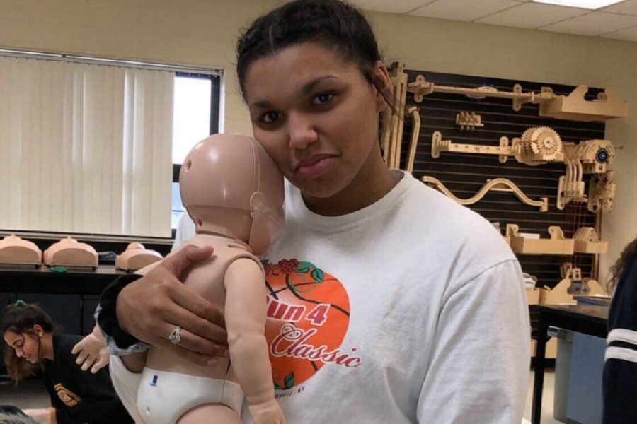 Senior Mackenzie Ramey holds a CPR training baby in human anatomy class. Ramey and her classmates were being trained in CPR on Wednesday, Dec. 5.