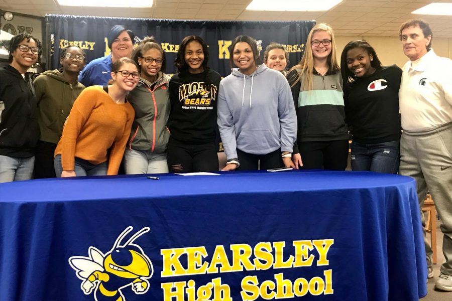 Senior Zaria Mitchner (middle with black shirt) poses with her teammates and coaches after signing her National Letter of Intent with Mott Community College to play basketball.