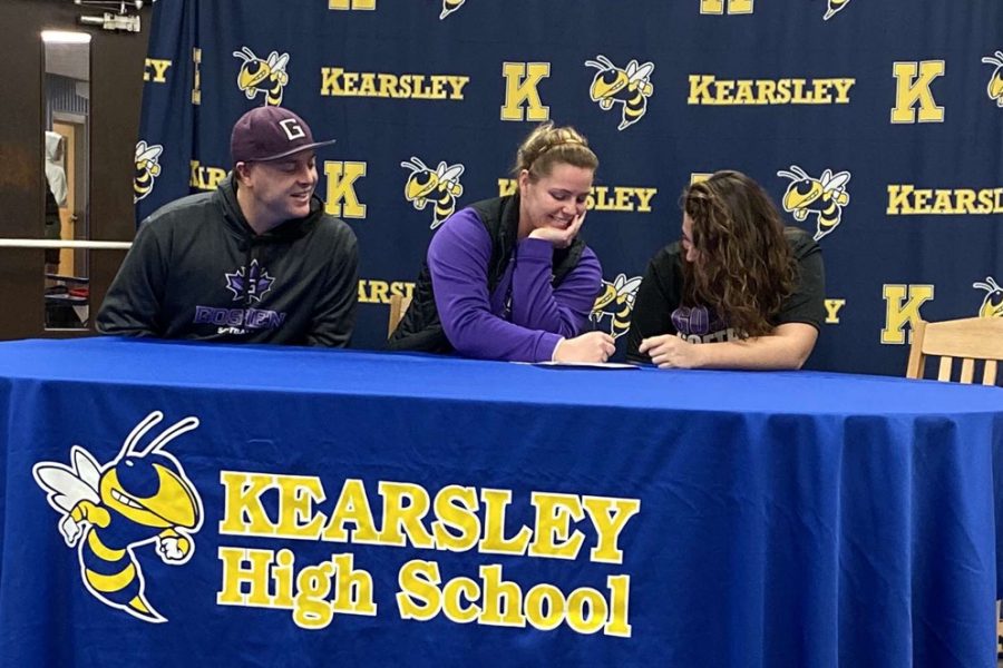 Senior Claire Ouellettes college coaches (left and center) watch as she signs her National Letter of Intent to play softball with Goshen College.