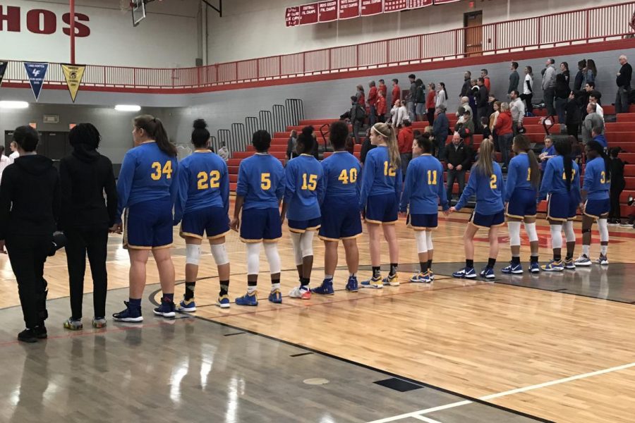 The girls basketball team links up for the national anthem before a 52-44 victory over Holly Friday, Jan. 17.