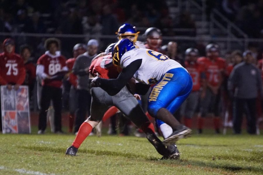 Senior Amari Douglas (No. 66) tackles a Holly ball carrier in a Metro League football game.