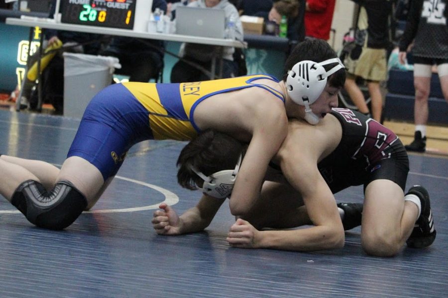 Freshman Keegan Doyle (top) works to pin his opponent at the Grass Lake Individual Tournament Saturday, Feb. 1.